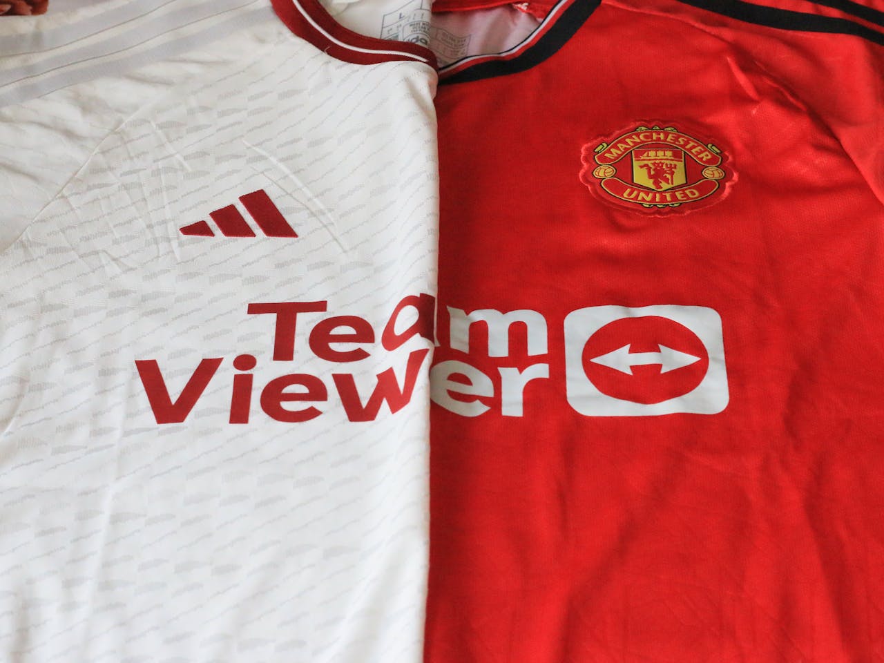 creative-03 Close-up of Manchester United 2023 jerseys showcasing red and white designs.